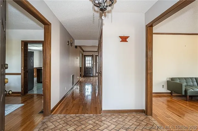 a view of a hallway to a livingroom with wooden floor and furniture