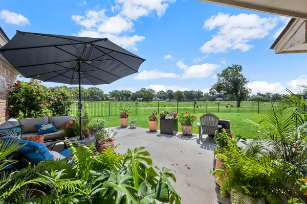 a view of a garden with lawn chairs under an umbrella