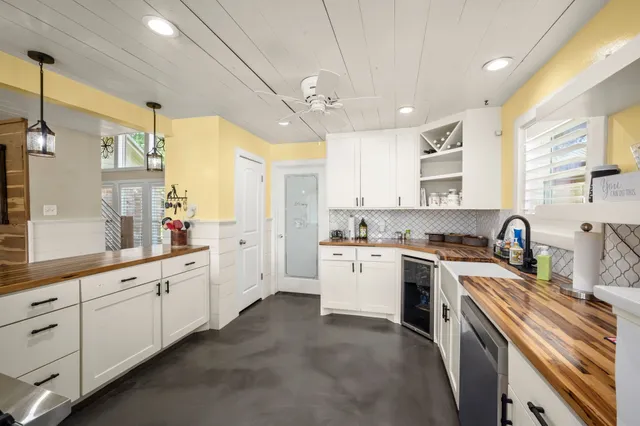 a kitchen with a sink dishwasher stove and white cabinets with wooden floor