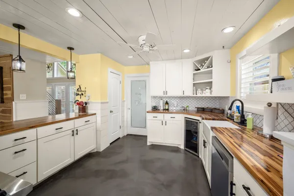 a kitchen with a sink dishwasher stove and white cabinets with wooden floor