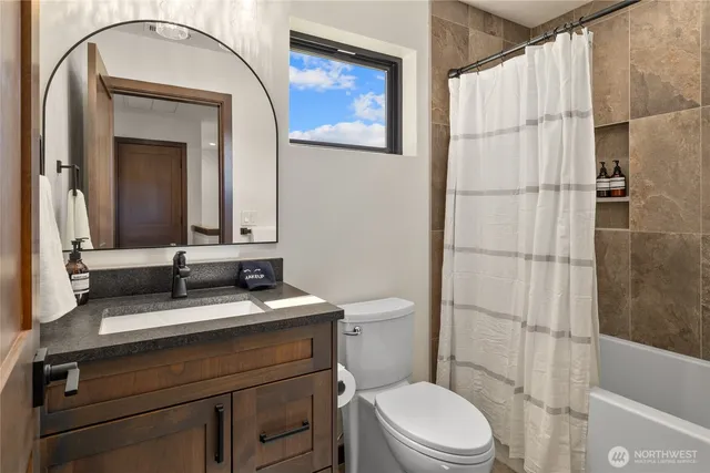 a bathroom with a granite countertop toilet sink and mirror