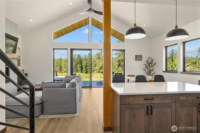 a view of a kitchen with kitchen island a large window cabinets a sink and stainless steel appliances