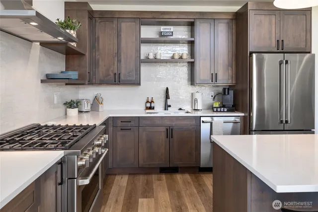 a kitchen with stainless steel appliances a refrigerator a sink and wooden cabinets