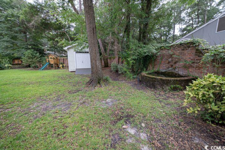 936 Oak Ridge Place Myrtle Beach, SC 29572 - Photo 29 of 36 View of green lawn featuring a shed, a playground, and view of scattered trees