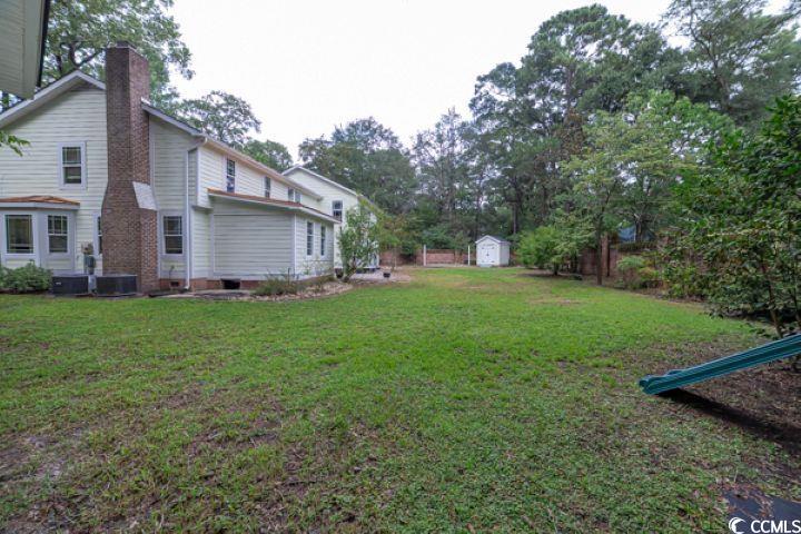 936 Oak Ridge Place Myrtle Beach, SC 29572 - Photo 4 of 36 View of grassy yard featuring a storage unit and view of wooded area