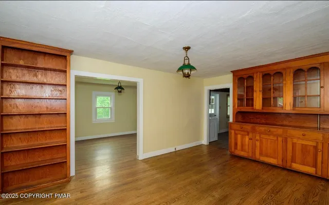 a view of an empty room with window and wooden floor