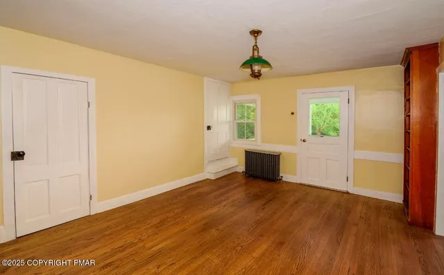 a view of an empty room with a window and wooden floor