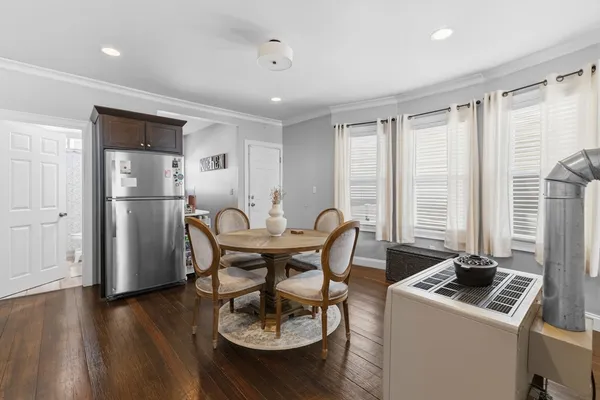 a kitchen with stainless steel appliances granite countertop a stove a refrigerator a microwave a dining table and chairs with wooden floor