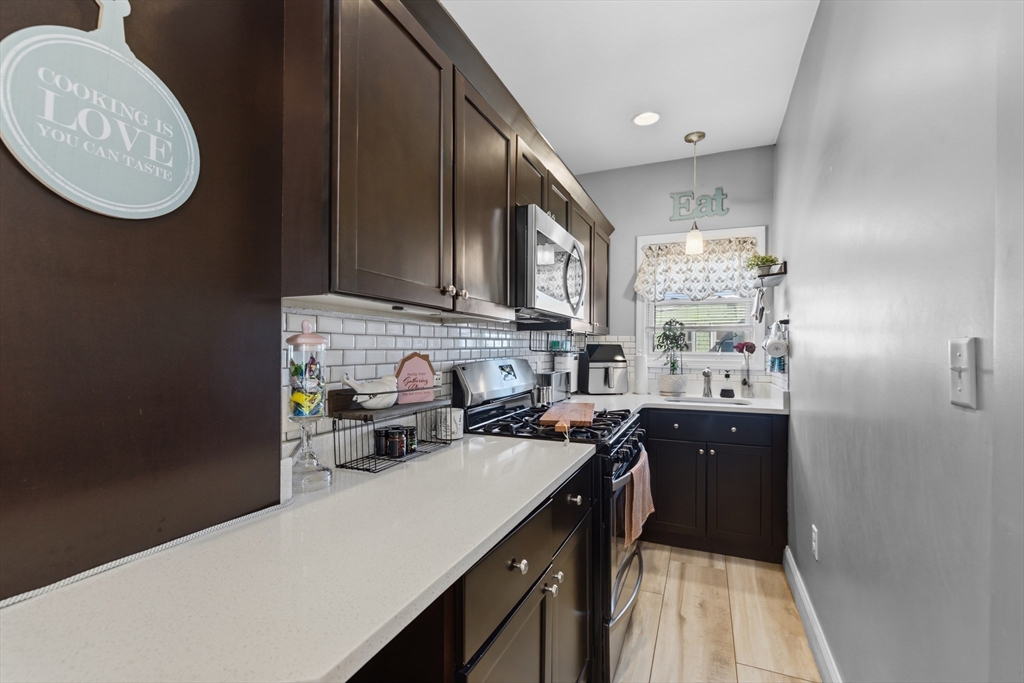 233 Belleville Road New Bedford, MA 02745 - Photo 18 of 40 a kitchen with granite countertop a sink a stove and cabinets