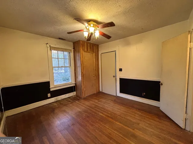 a view of an empty room with window and wooden floor