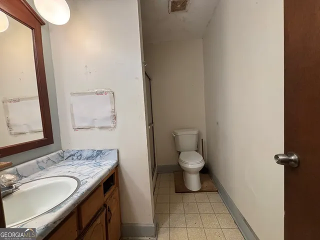 a bathroom with a granite countertop toilet and a sink