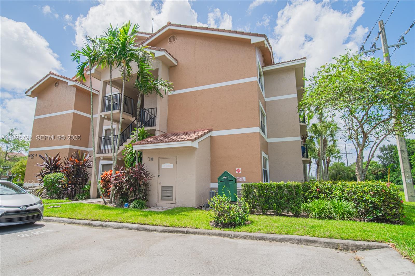 9033 Wiles Road, Unit 303 Coral Springs, FL 33067 - Photo 2 of 17 front view of house with potted plants and palm trees