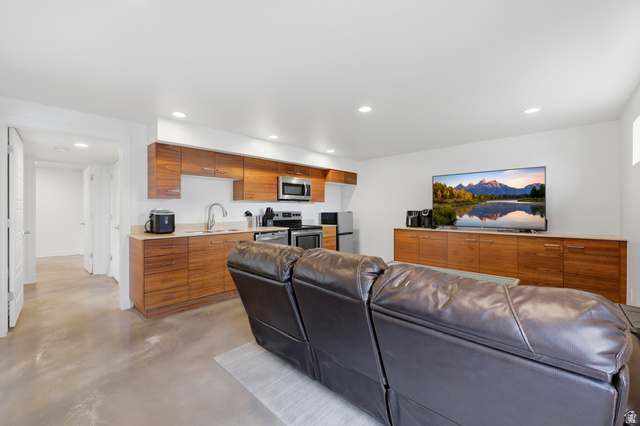 1389 Millbrook Way Bountiful, UT 84010 - Photo 43 of 74 Open concept living space featuring a full kitchen with stainless steel appliances, wood-finish cabinetry, and solid surface countertops