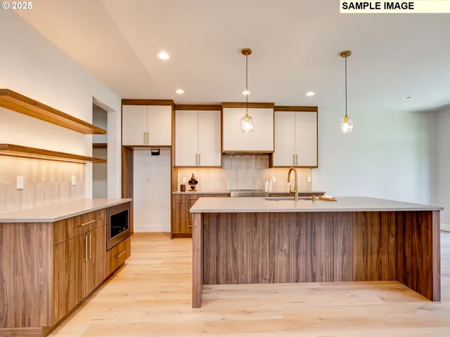 a large kitchen with a large counter top a sink stainless steel appliances and cabinets