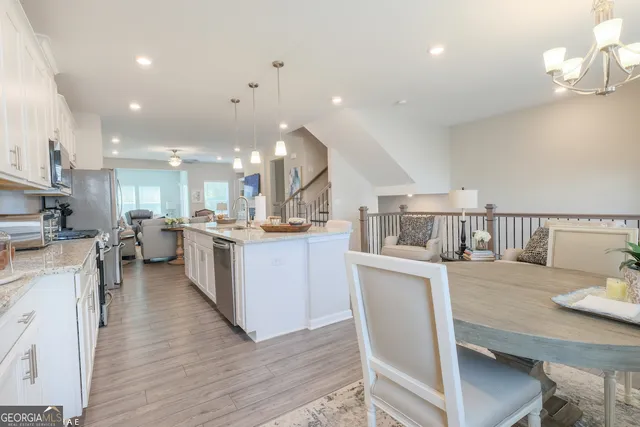 a kitchen with stainless steel appliances kitchen island granite countertop a table chairs and a refrigerator