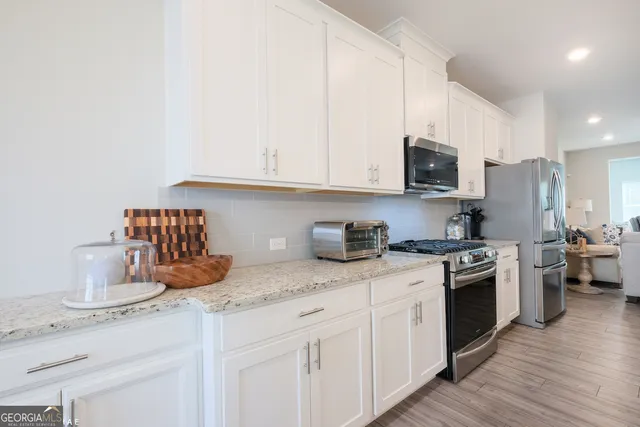 a kitchen with granite countertop white cabinets and stainless steel appliances