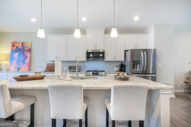 a kitchen with stainless steel appliances granite countertop a sink a stove a refrigerator cabinets and chairs