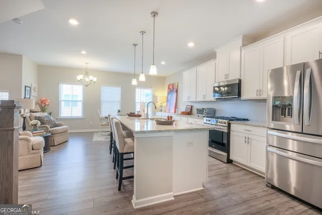 a kitchen with stainless steel appliances granite countertop a refrigerator a stove top oven a sink dishwasher and white cabinets with wooden floor