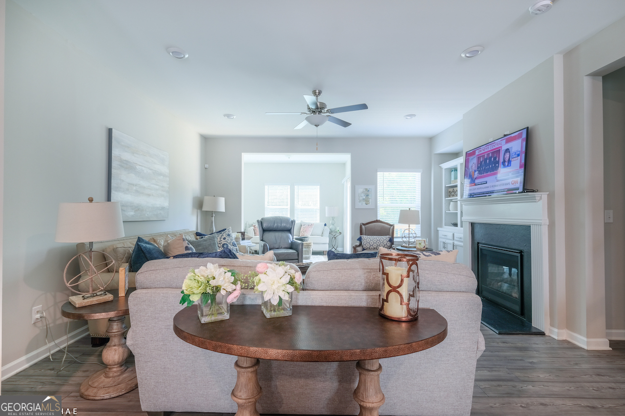 2247 Pink Hawthorn Drive Buford, GA 30518 - Photo 6 of 43 a living room with couches a fireplace and a dining table with wooden floor