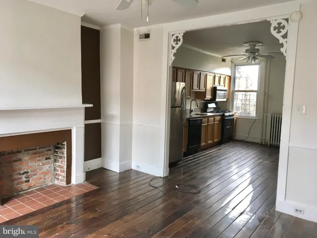 an empty room with windows a fireplace and wooden floor