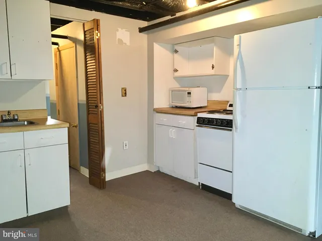 a kitchen with a refrigerator and white cabinets