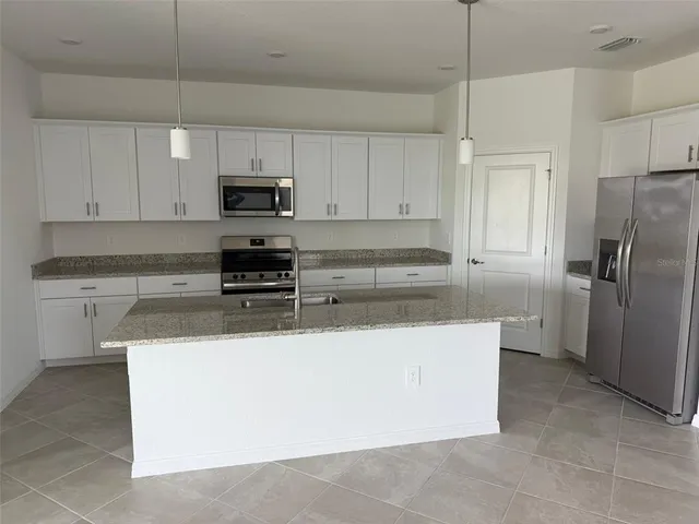 a kitchen with stainless steel appliances a refrigerator a stove a sink and white cabinets