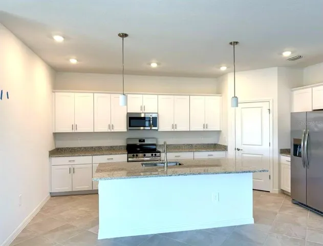 a kitchen with stainless steel appliances granite countertop a sink a stove a refrigerator a center island and cabinets