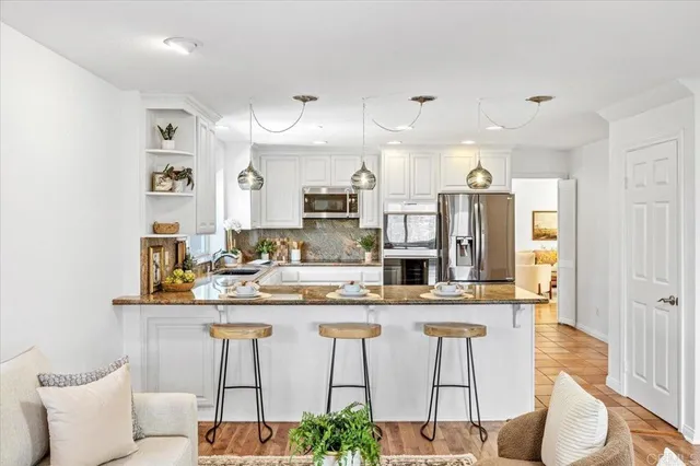 a kitchen with stainless steel appliances kitchen island granite countertop a table and chairs