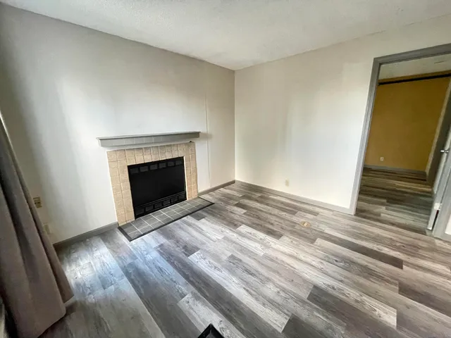 a view of empty room with wooden floor and fireplace