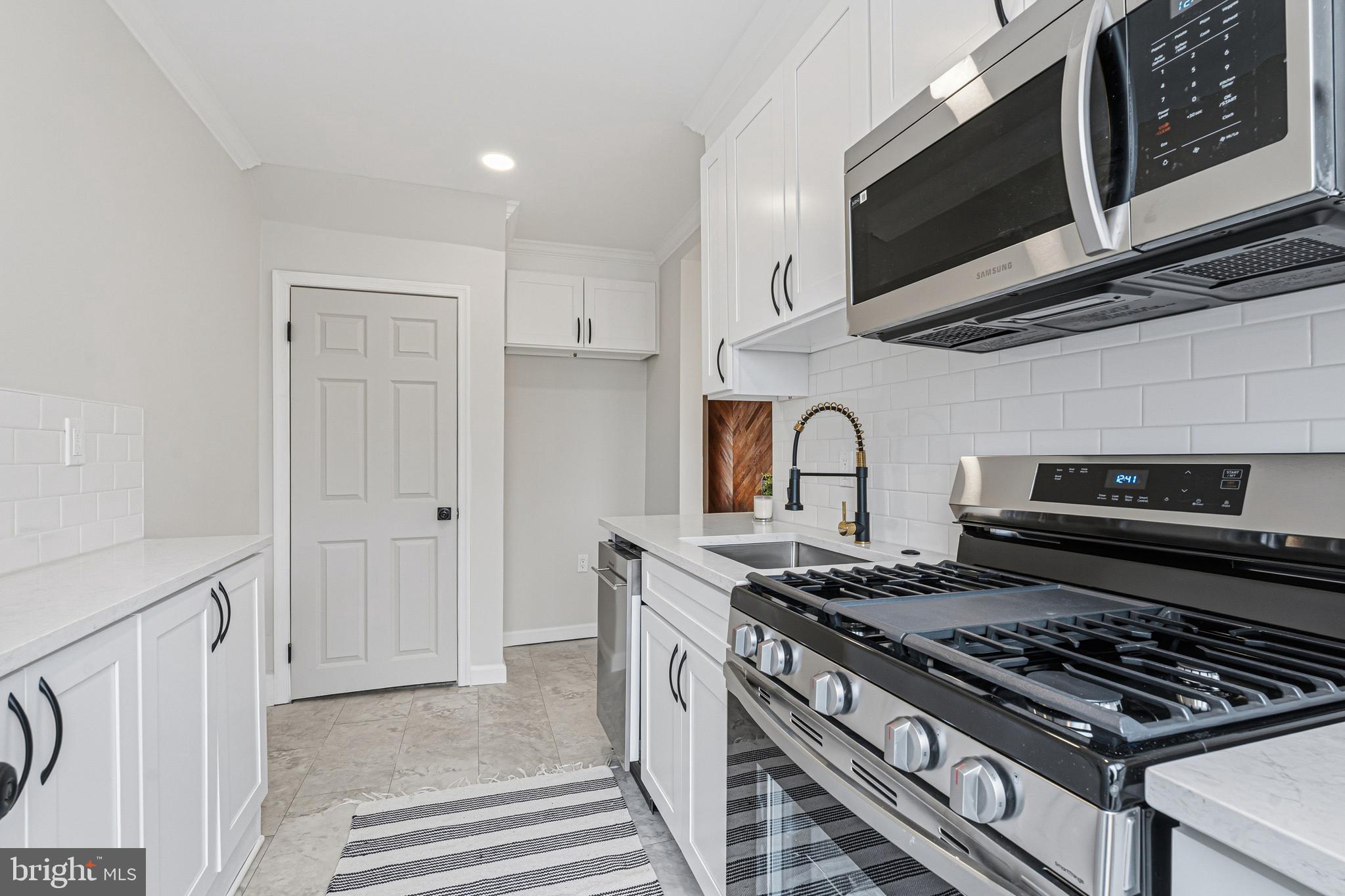 1326 Tompkins Street Baltimore, MD 21225 - Photo 9 of 34 a kitchen with stainless steel appliances granite countertop a stove and a microwave