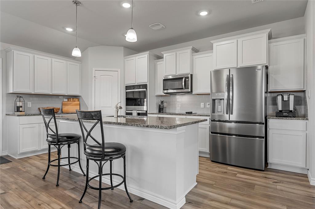 10761 Chesson Flts Drive Waco, TX 76708 - Photo 10 of 30 a kitchen with stainless steel appliances granite countertop a refrigerator a stove a sink a dining table and chairs with wooden floor