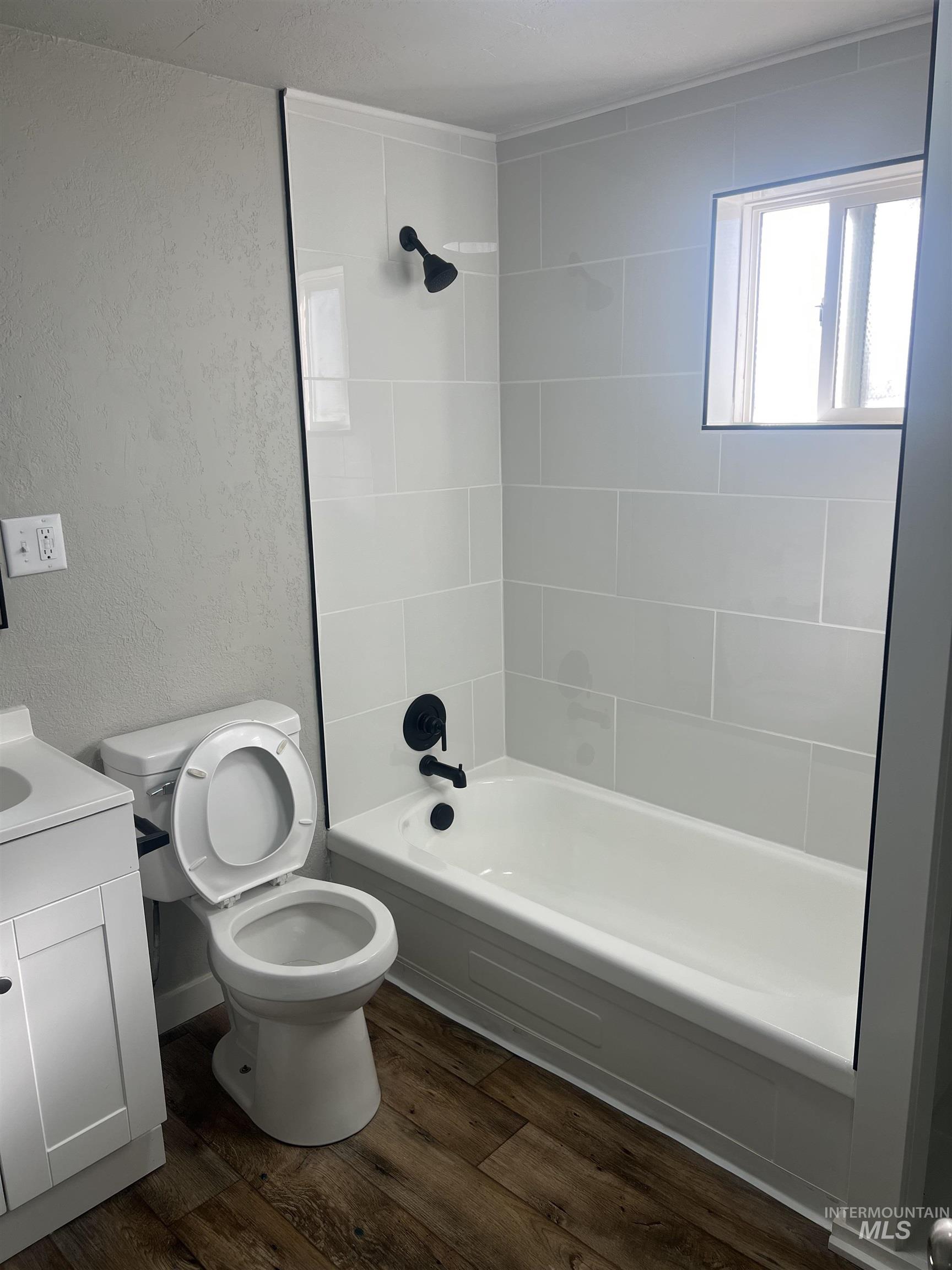 150 Roosevelt Street Mountain Home, ID 83647 - Photo 12 of 16 Full bath with a textured wall, shower / bathtub combination, dark wood finished floors, and vanity