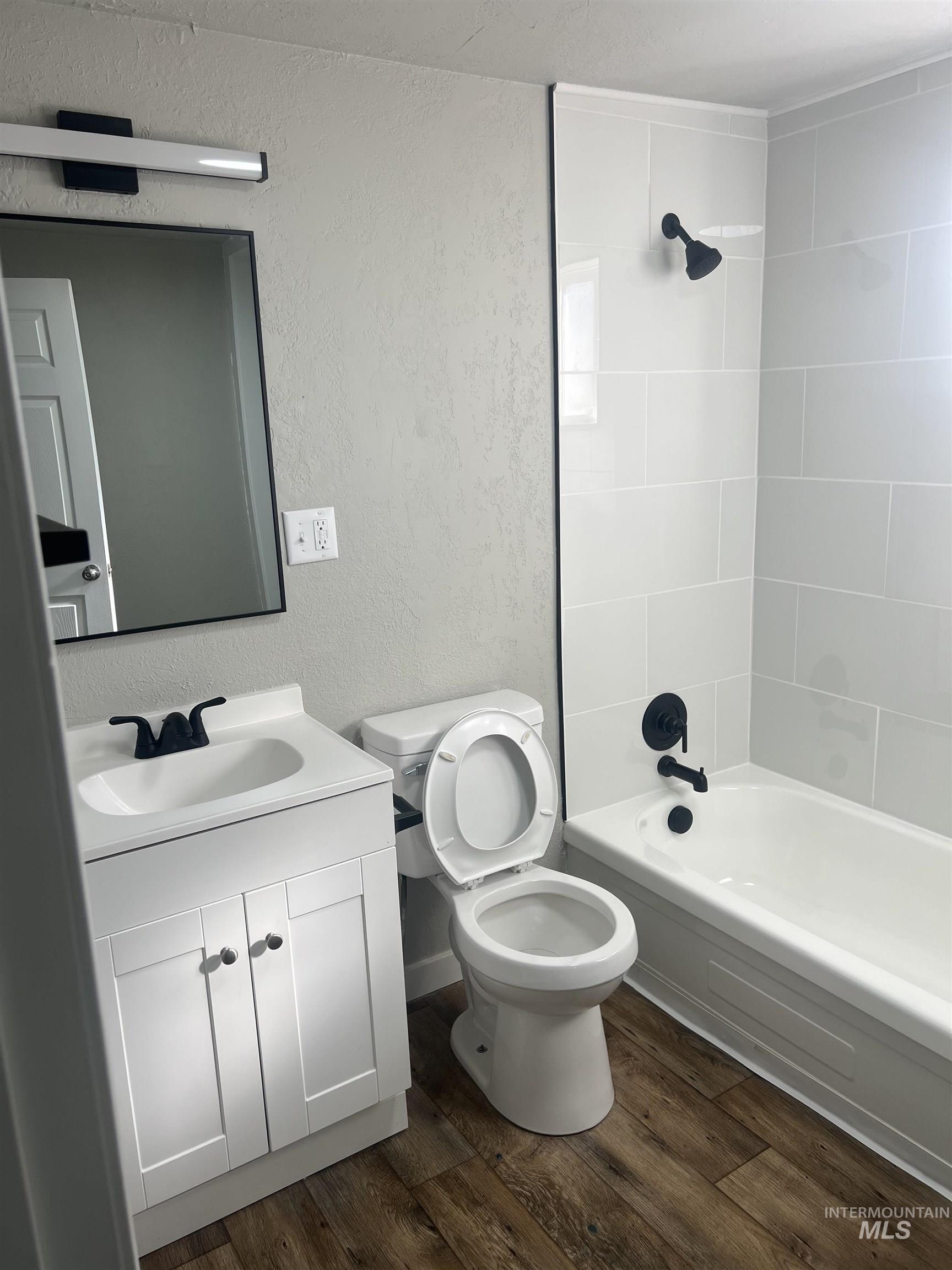 150 Roosevelt Street Mountain Home, ID 83647 - Photo 13 of 16 Bathroom featuring a textured wall, dark wood-style flooring, bathing tub / shower combination, and vanity