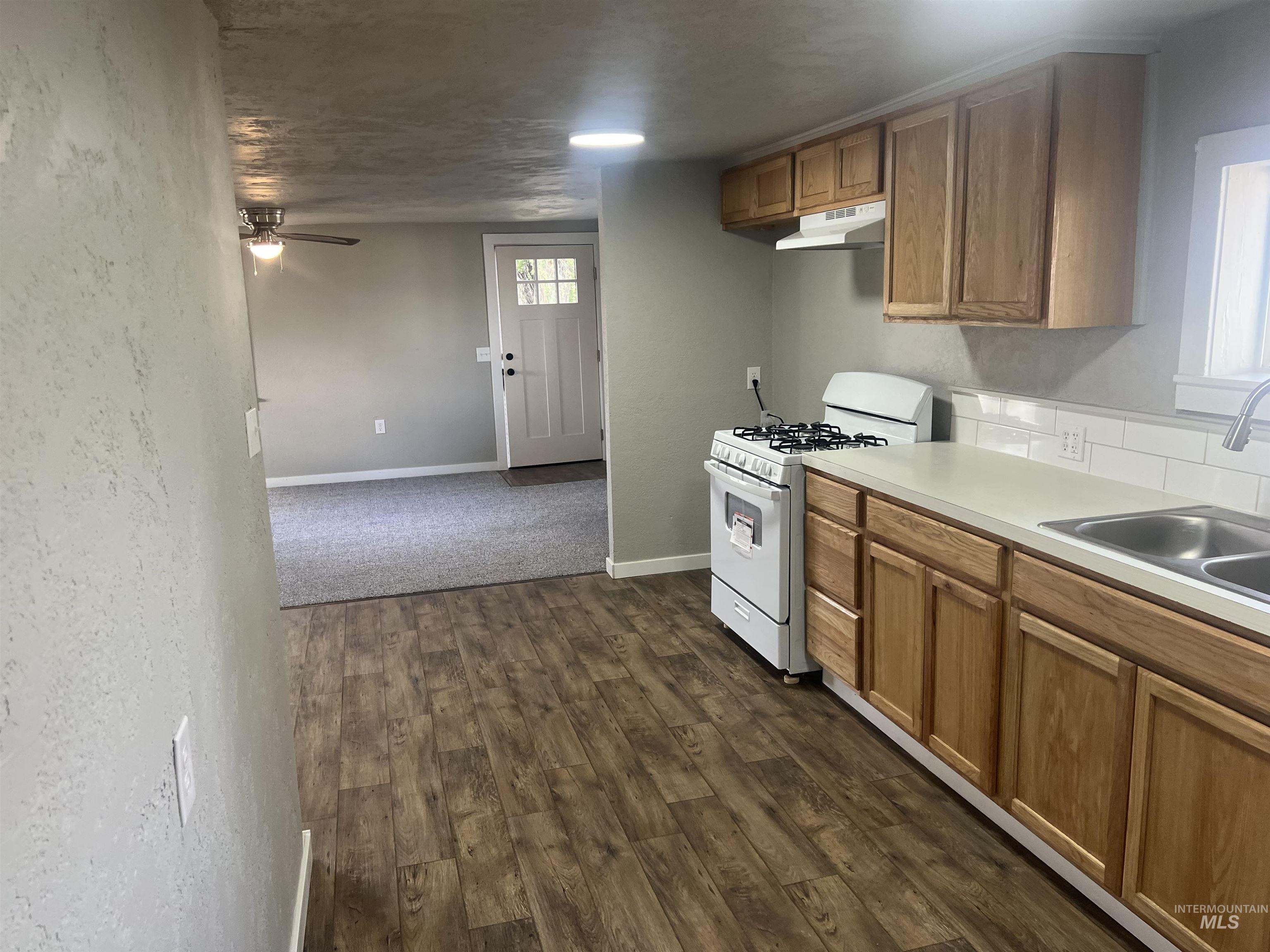 150 Roosevelt Street Mountain Home, ID 83647 - Photo 6 of 16 Kitchen featuring gas range gas stove, light countertops, dark wood-style floors, brown cabinetry, and a ceiling fan