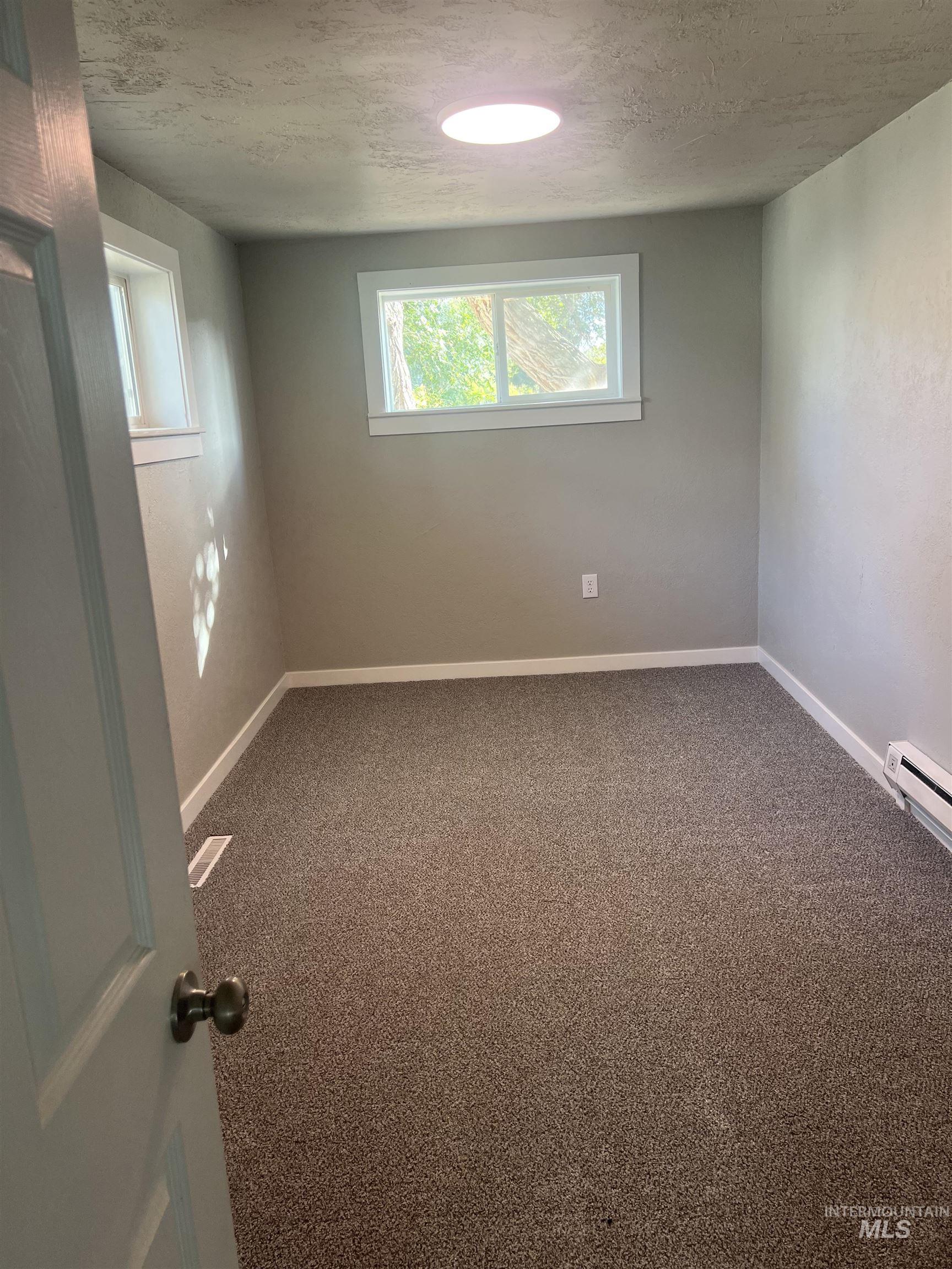 150 Roosevelt Street Mountain Home, ID 83647 - Photo 9 of 16 Empty room with carpet, a textured ceiling, and a baseboard radiator