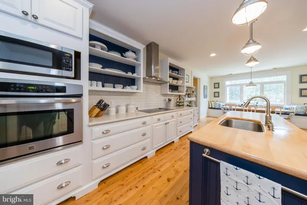 a large kitchen with stainless steel appliances granite countertop a large stove a sink dishwasher and a fireplace with wooden floor