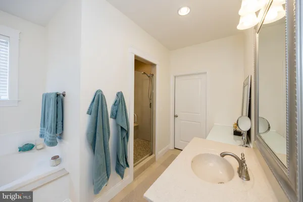 a spacious bathroom with a granite countertop sink and a bathtub