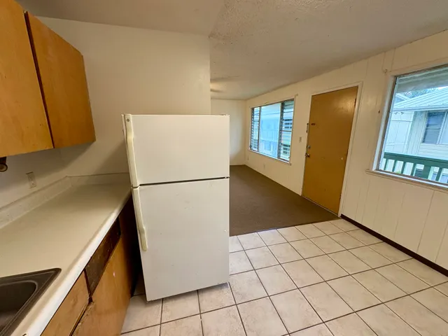 a view of a kitchen with refrigerator and white cabinets