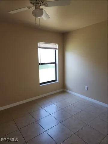 an empty room with a chandelier fan and windows