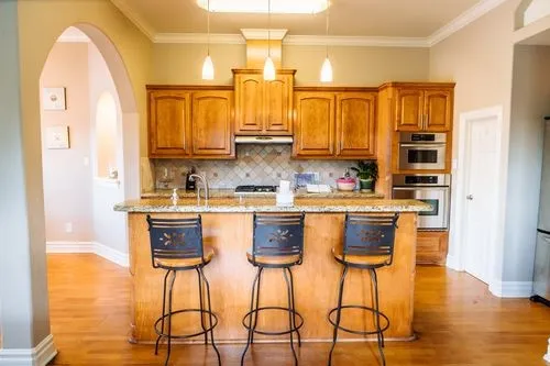 a kitchen with stainless steel appliances granite countertop a refrigerator a stove a sink and white cabinets with wooden floor