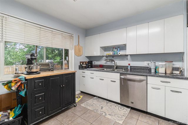 a kitchen with granite countertop cabinets stainless steel appliances a sink and a large window