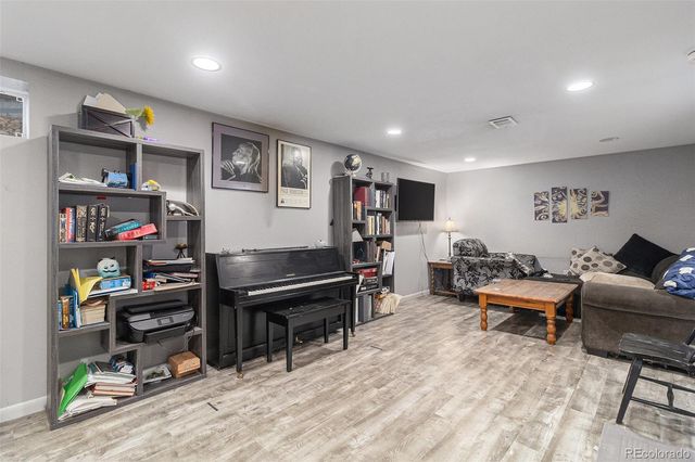 a living room with furniture a piano and a bookshelf
