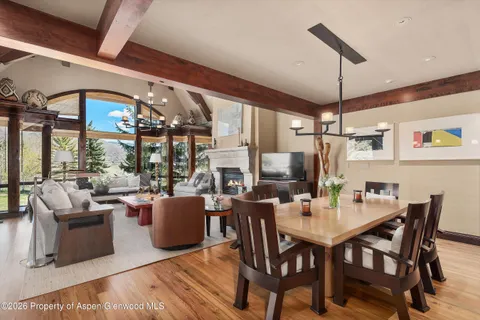 a dining room with wooden floor a chandelier a wooden table and chairs