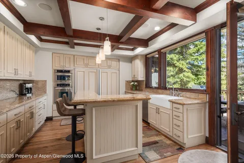 a kitchen with kitchen island granite countertop a sink a counter top space stainless steel appliances and a large window