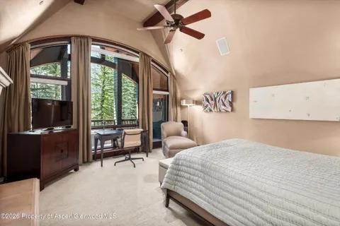 a bedroom with a bed and large windows