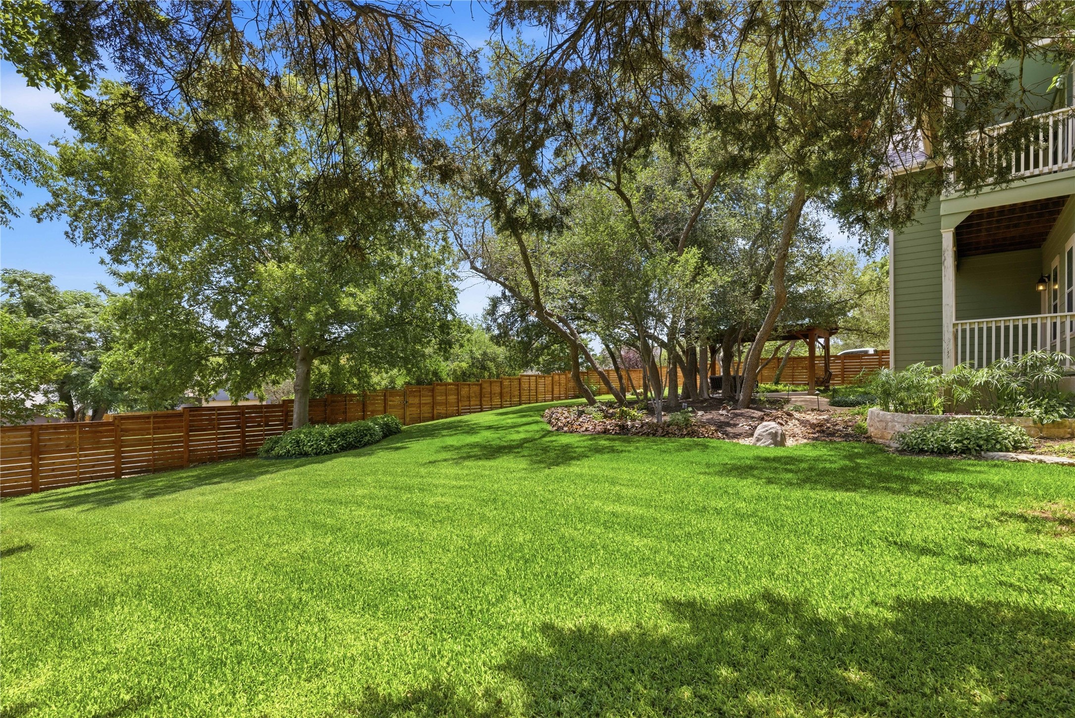 1204 Orlando Road Austin, TX 78733 - Photo 17 of 40 A verdant lawn gracefully slopes towards a sturdy wooden fence, offering a private outdoor sanctuary.