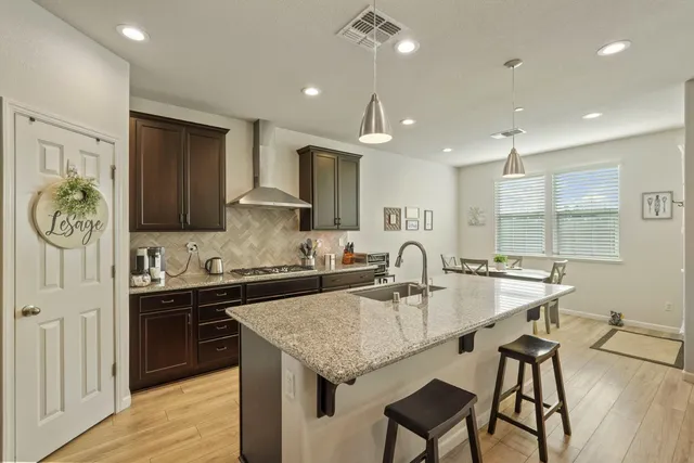 a kitchen with granite countertop kitchen island stainless steel appliances a sink and a refrigerator