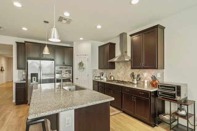 a kitchen with stainless steel appliances granite countertop a sink a stove counter space and cabinets