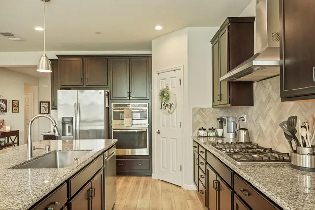 a kitchen with granite countertop a sink a stove and refrigerator