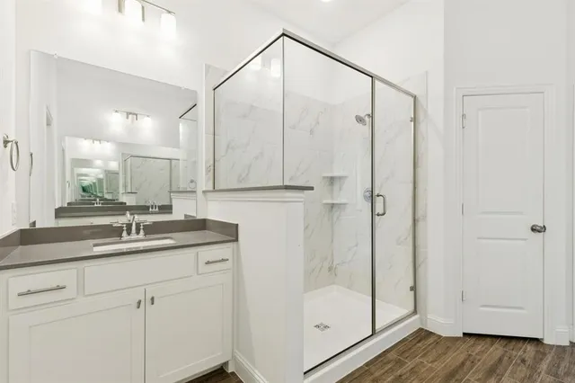 a bathroom with a granite countertop sink a mirror and shower